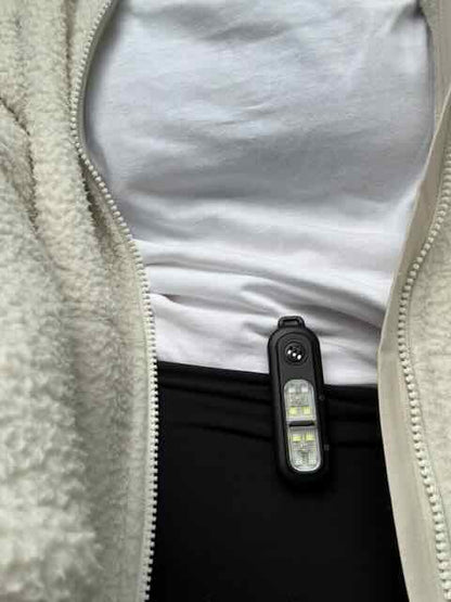 clip on personal safety alarm device attached to a person wearing a  fleece jacket.