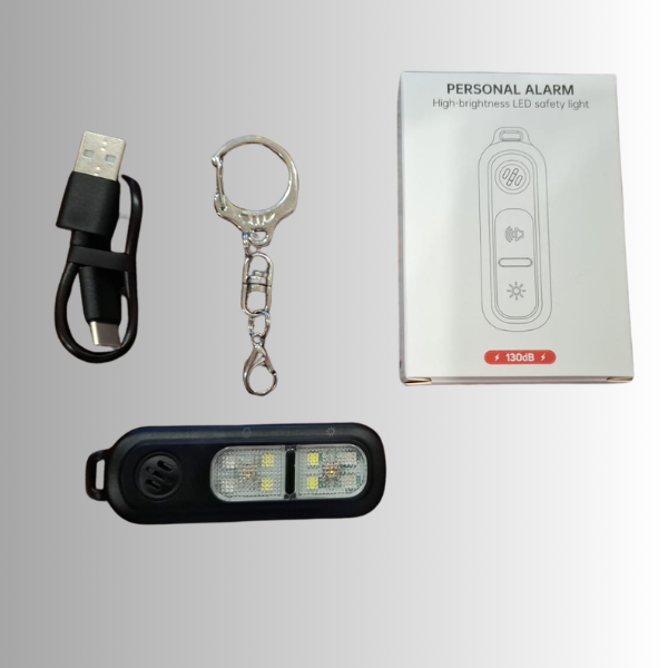 Clip on Personal alarm or can be used with keychain,  withLED safety light, a USB charging cable, a silver keychain clip, and the product packaging box on a light gray background.